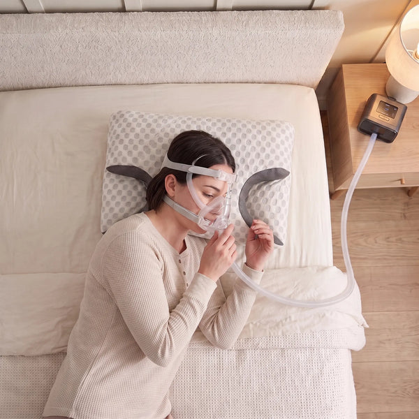 Woman lying on her side, mask and hose sliding into the pillow cutout