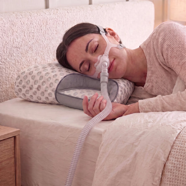 Head resting in contoured foam pillow, mask hose clear of the seal